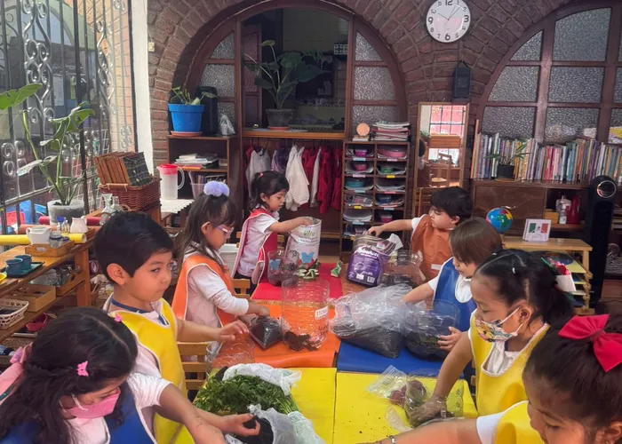 Niño mayor ayudando sutilmente a una niña pequeña con un material en el suelo